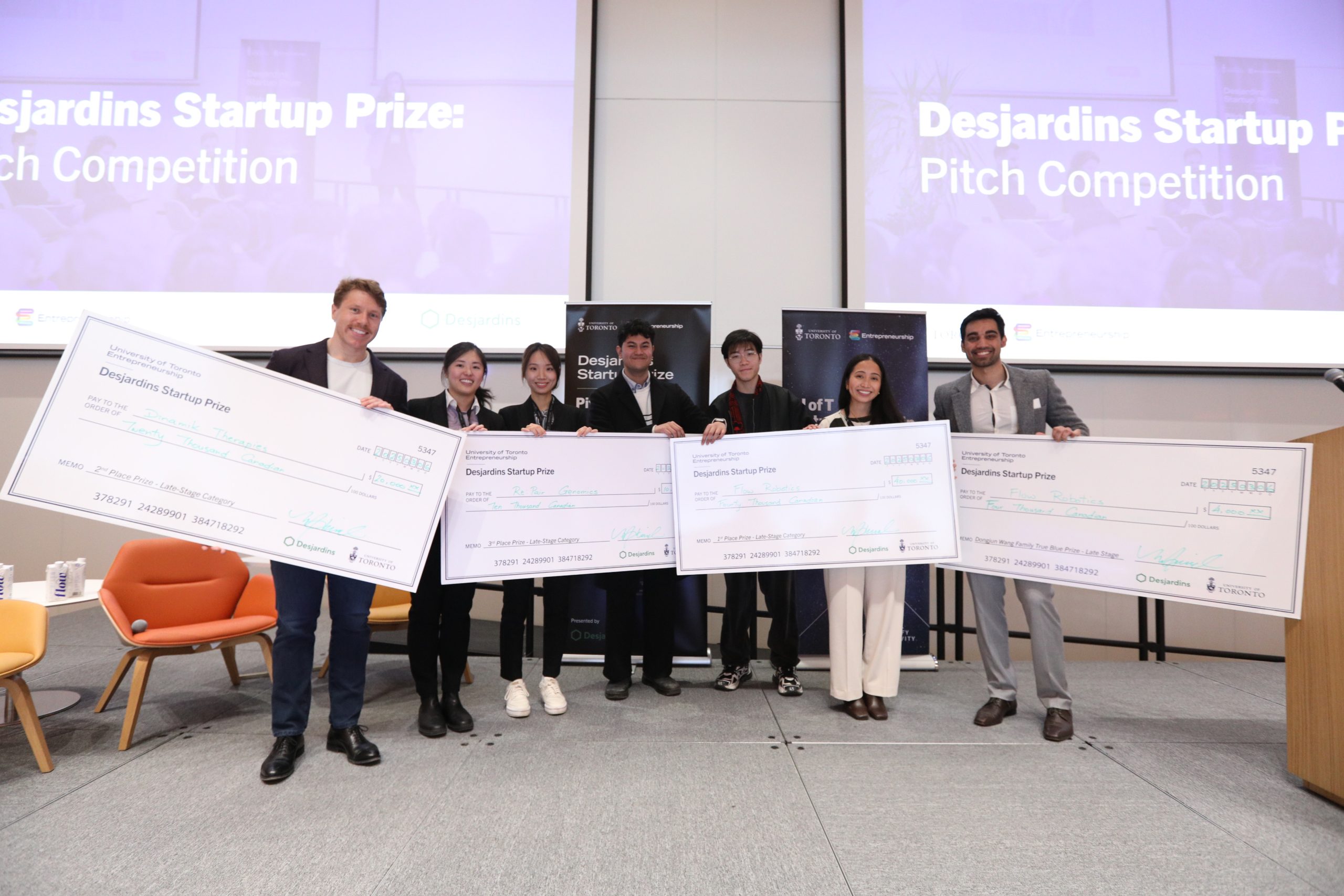 Late stage category winners holding up their cheques on stage
